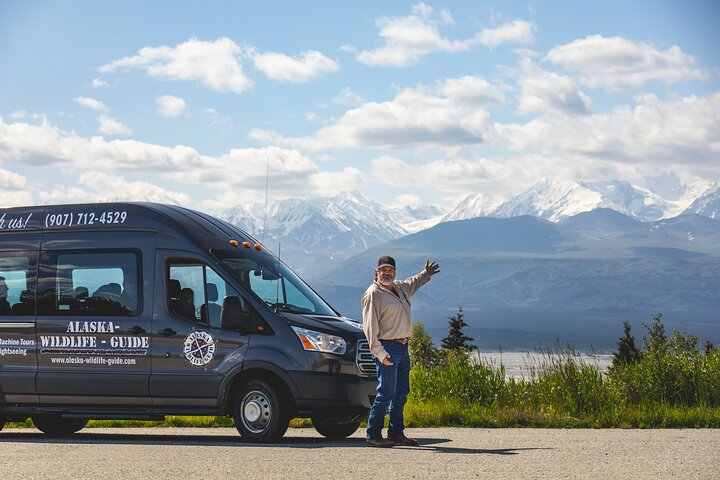 A tour guide with van in front of mountains